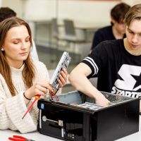 Några studerande demonterar en dator i ett klassrum