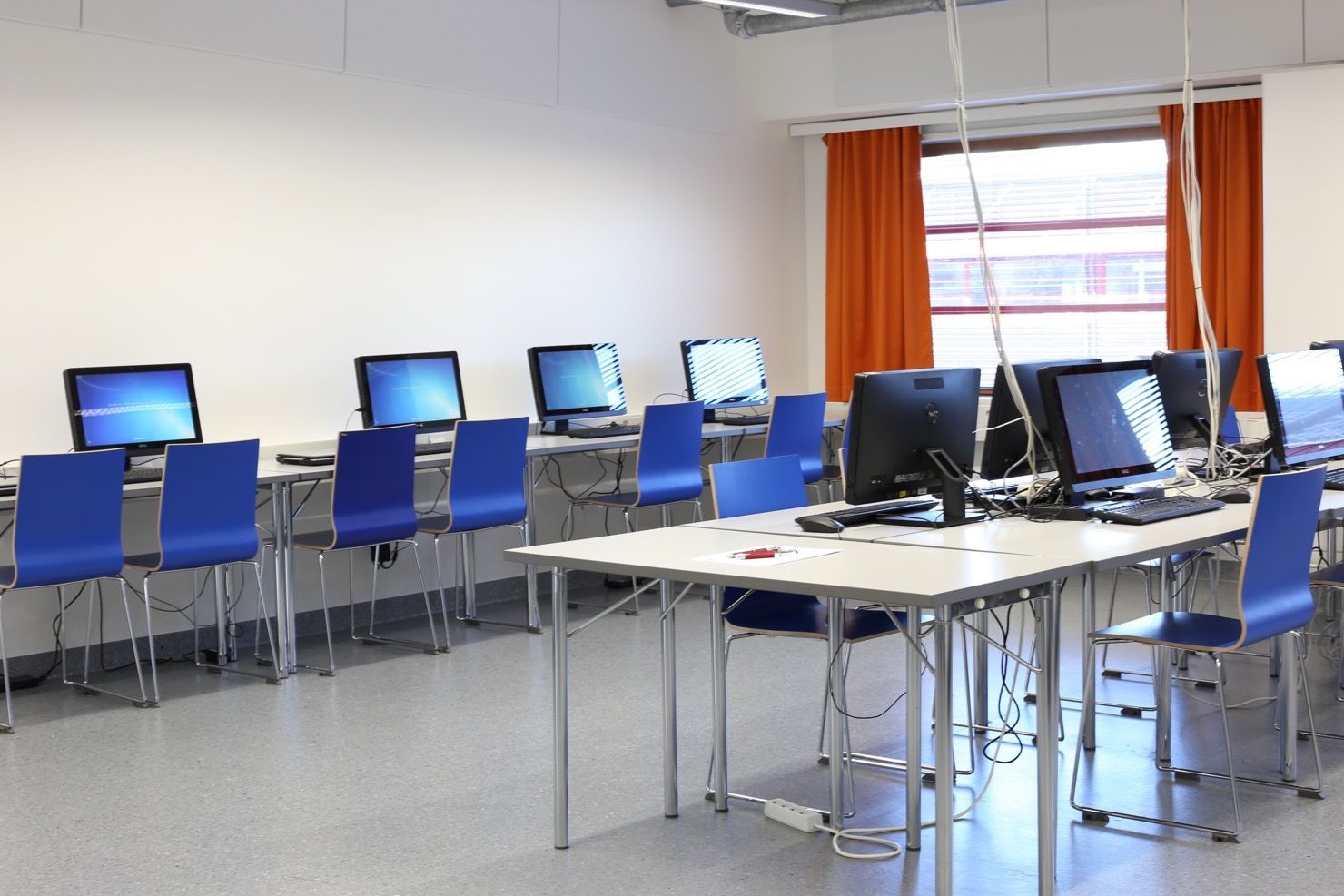 Dataklassutrymmen med blåa stolar och datorer framför på borden