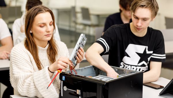 Några studerande demonterar en dator i ett klassrum