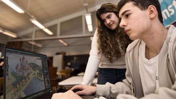 Två studerande ser på en laptop med Blender 3D programmet framme