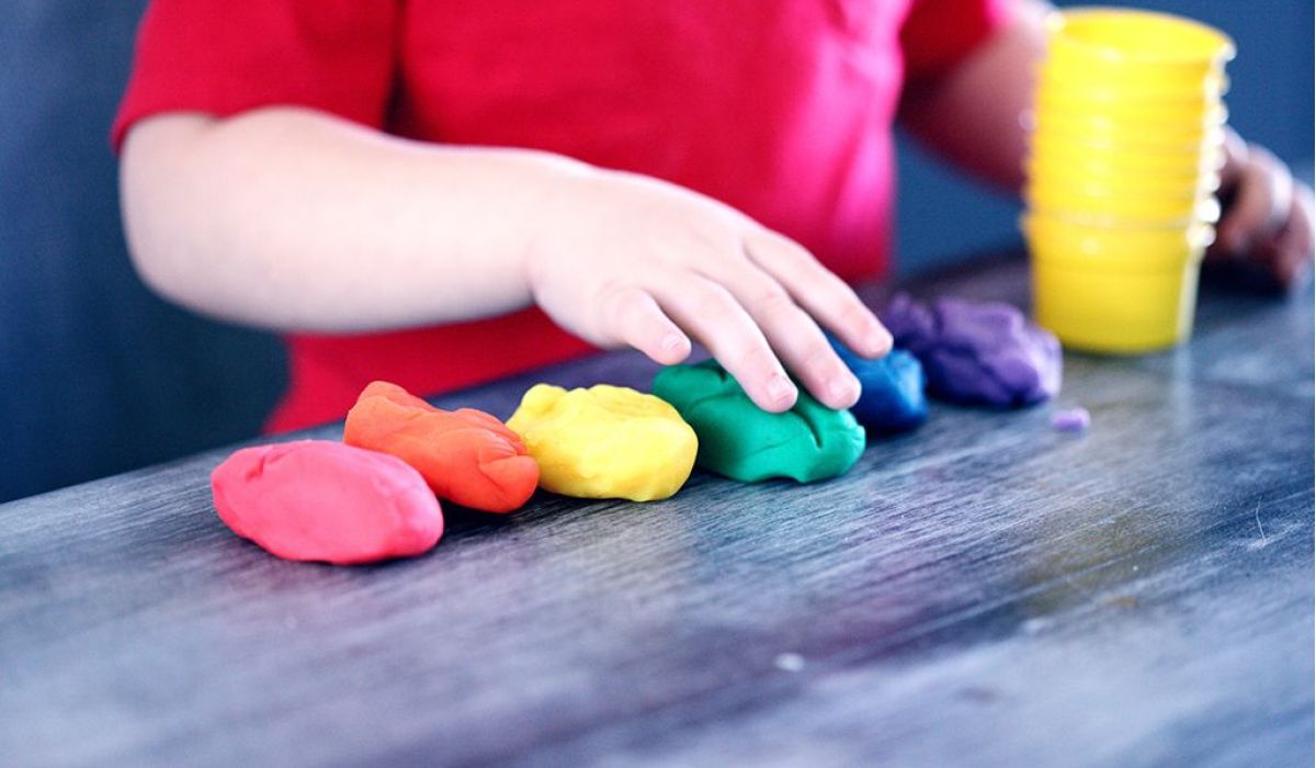 ett barn leker med modelera i olika färger